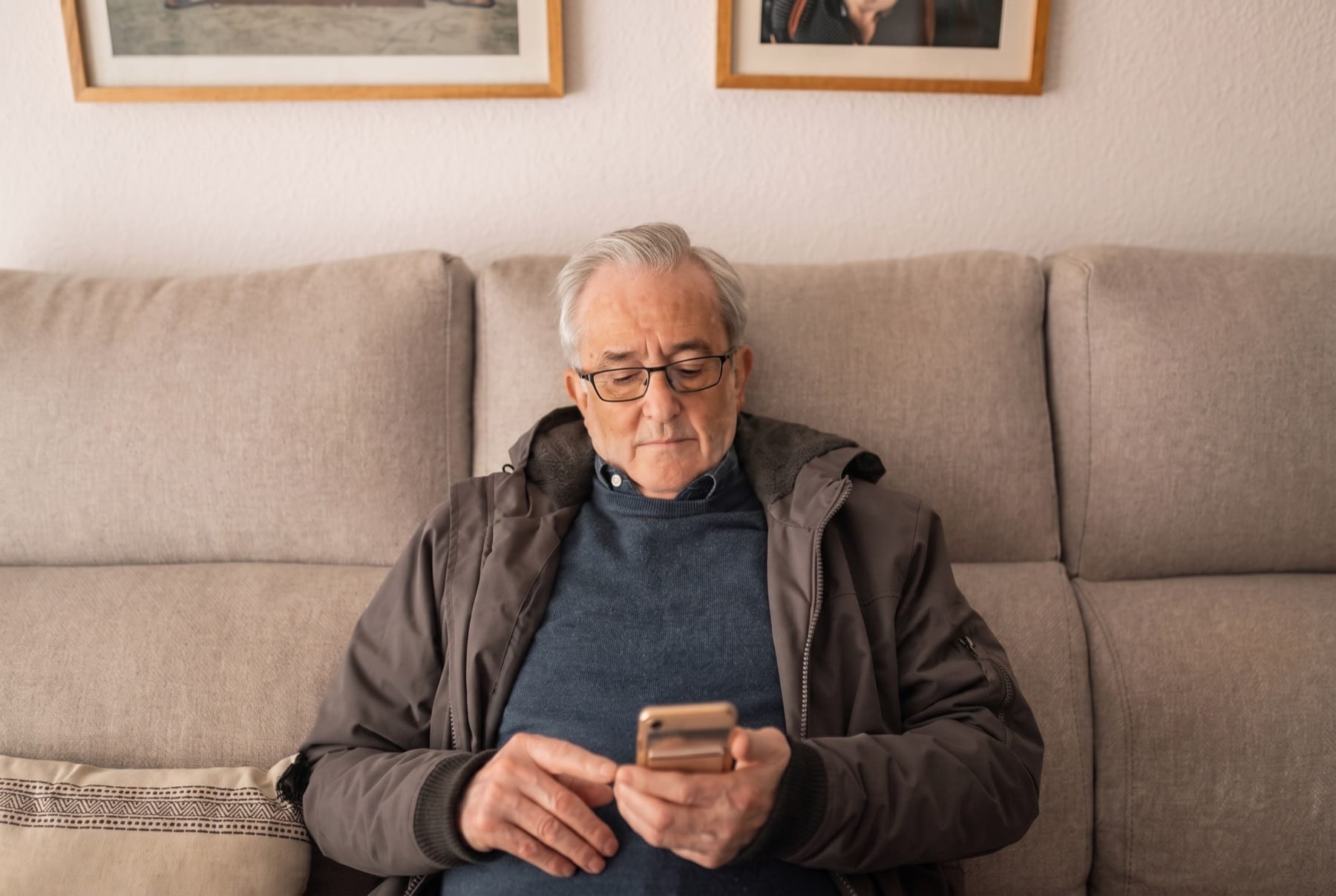 An older man at home looking at his phone.