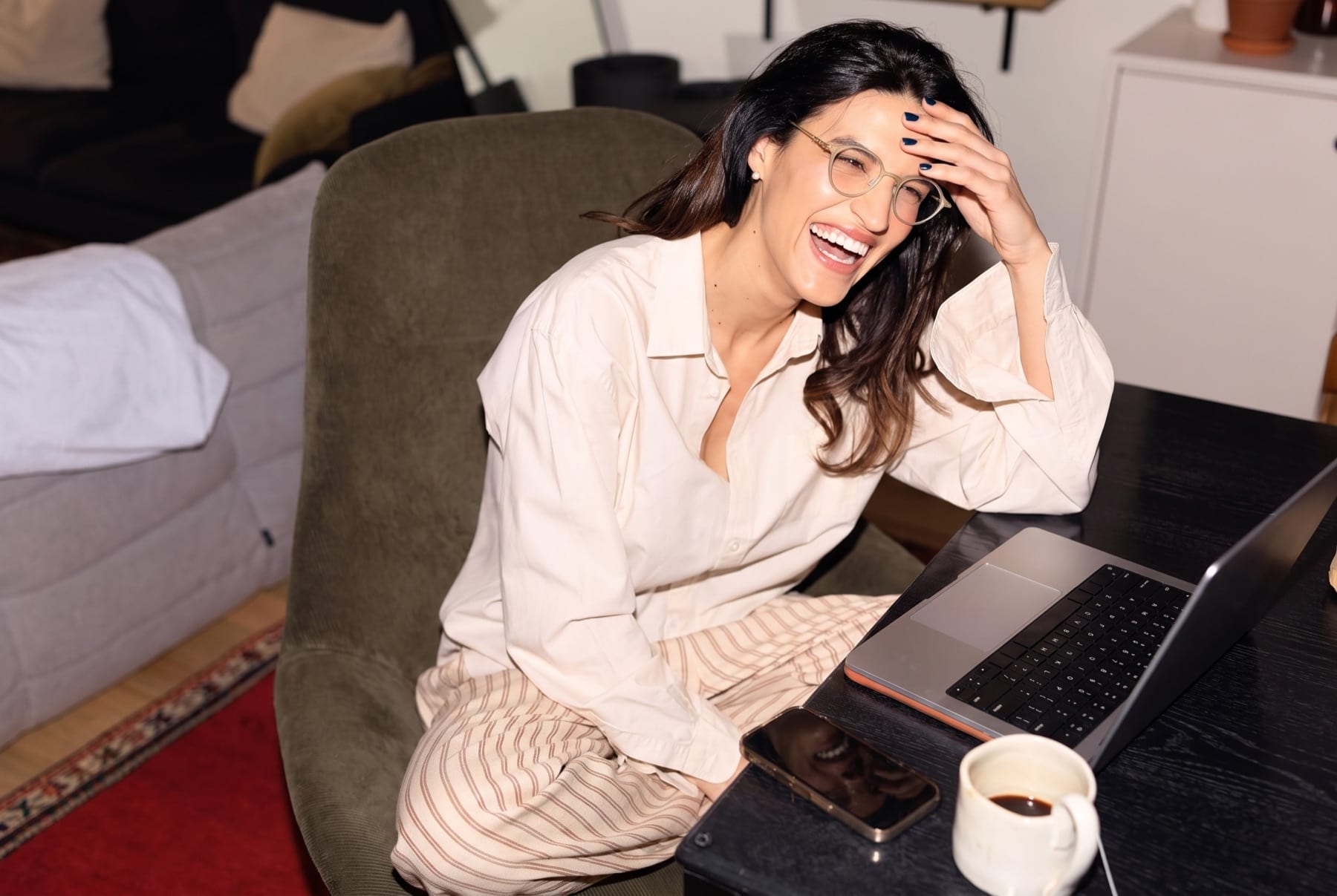 A woman smiling with relief while reviewing information on her laptop at home.
